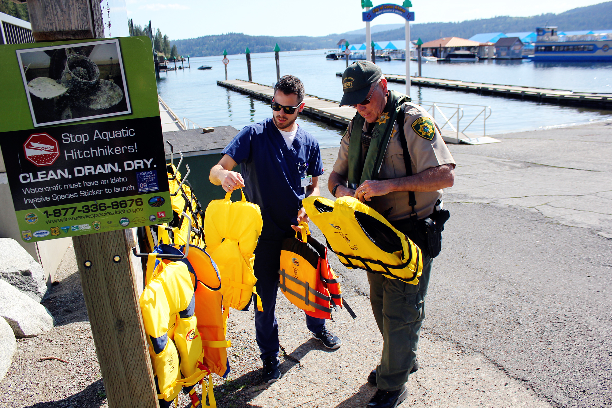 Deputy Bob Bjelland and Luke Emerson, Trauma Clinical Navigator, stock the life jacket station at the Third Street Marina. 